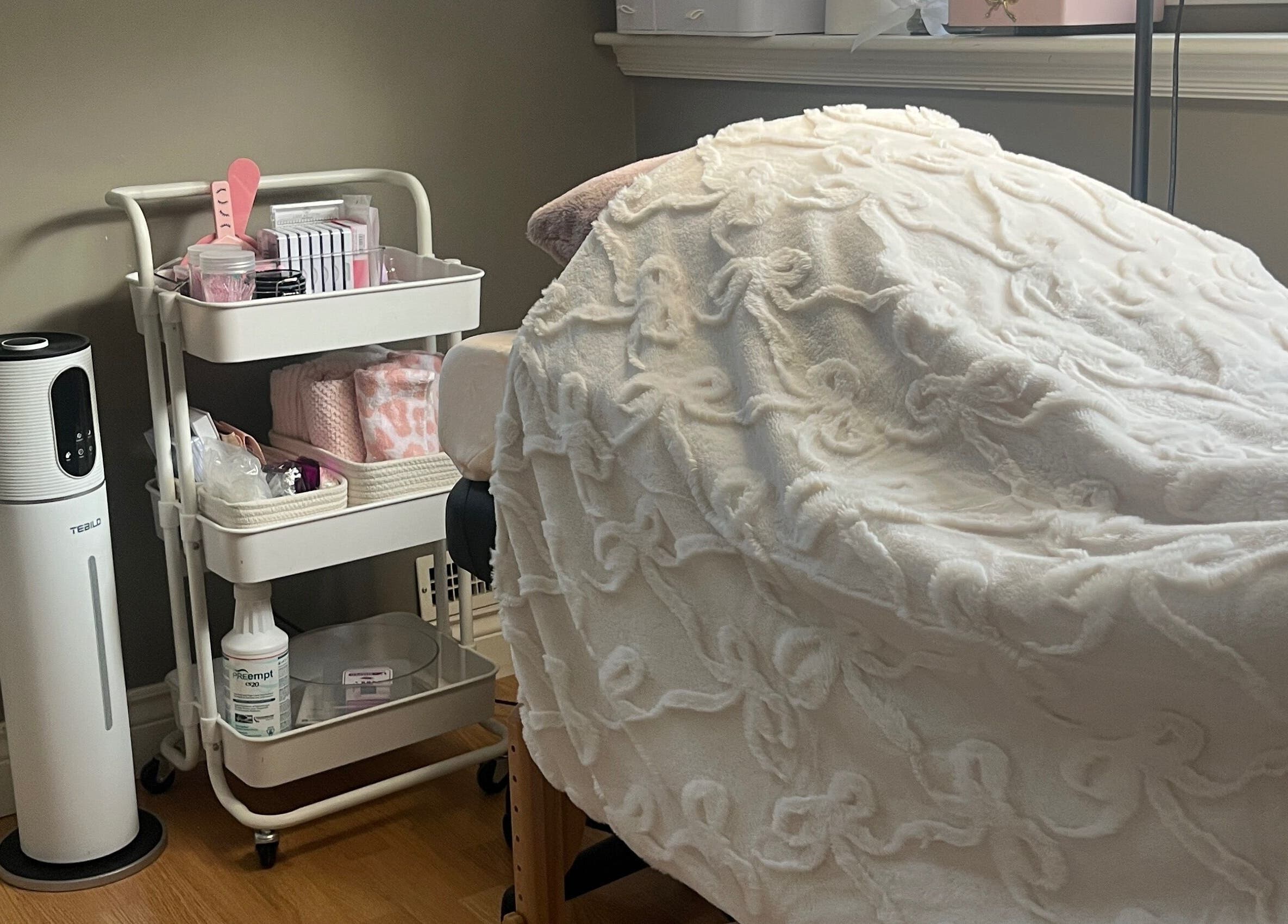Cozy treatment bed and supplies at Lovely Lash by Aria in Ayr, Ontario, CA, showcasing comfort and elegance.
