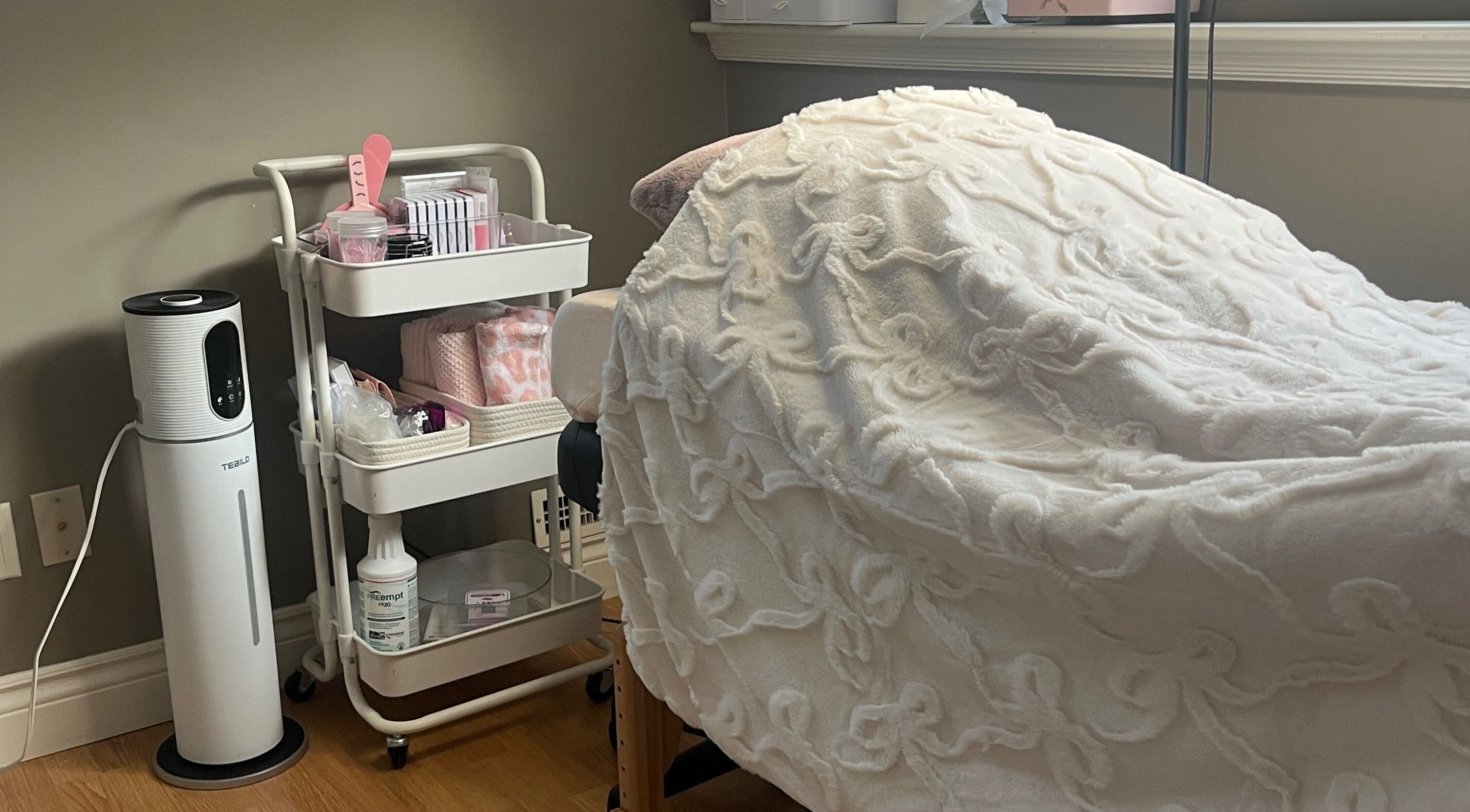 Cozy treatment bed and supplies at Lovely Lash by Aria in Ayr, Ontario, CA, showcasing comfort and elegance.
