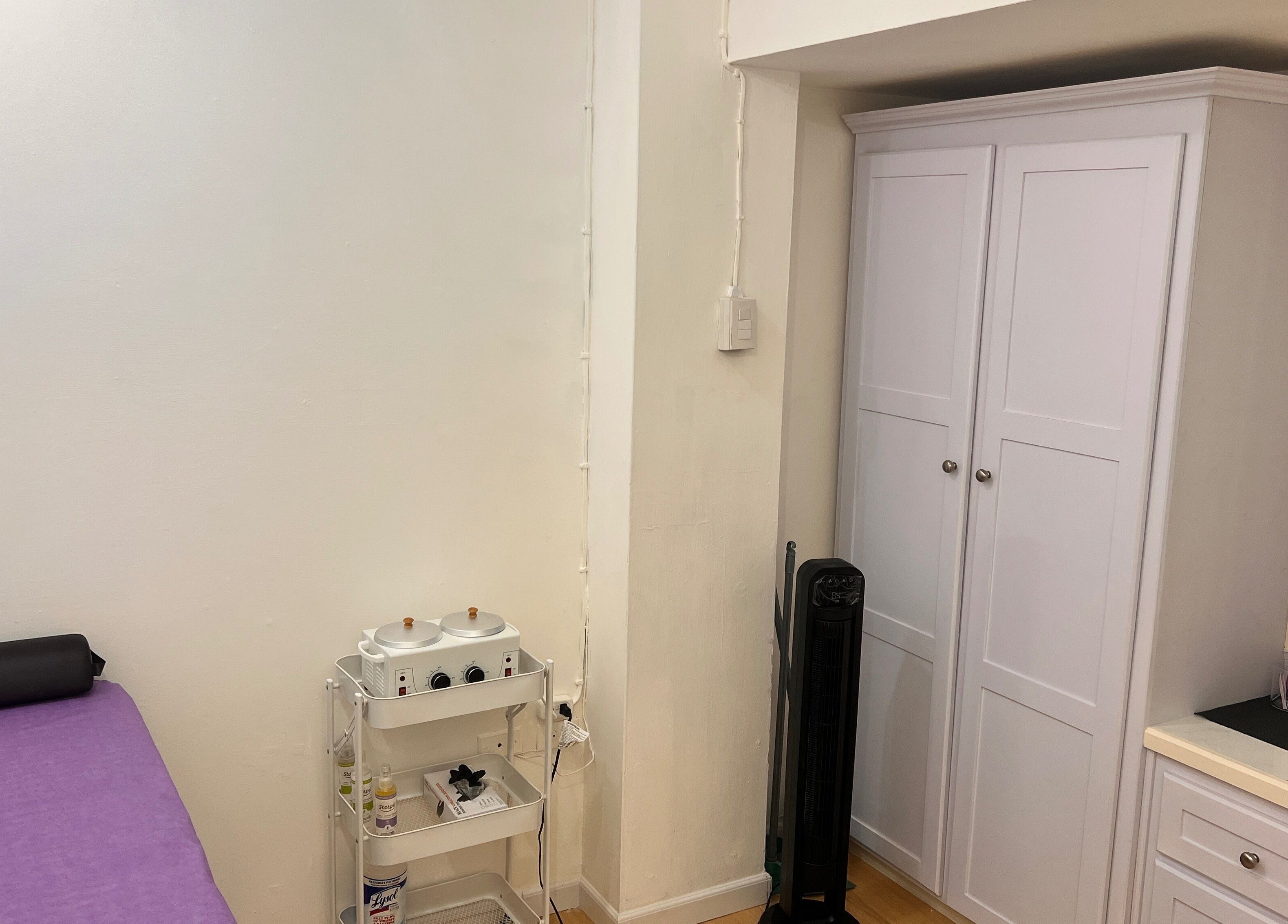 Tranquil treatment room at ACEluxeluminance in Port Of Spain, featuring a massage table and white cabinets.
