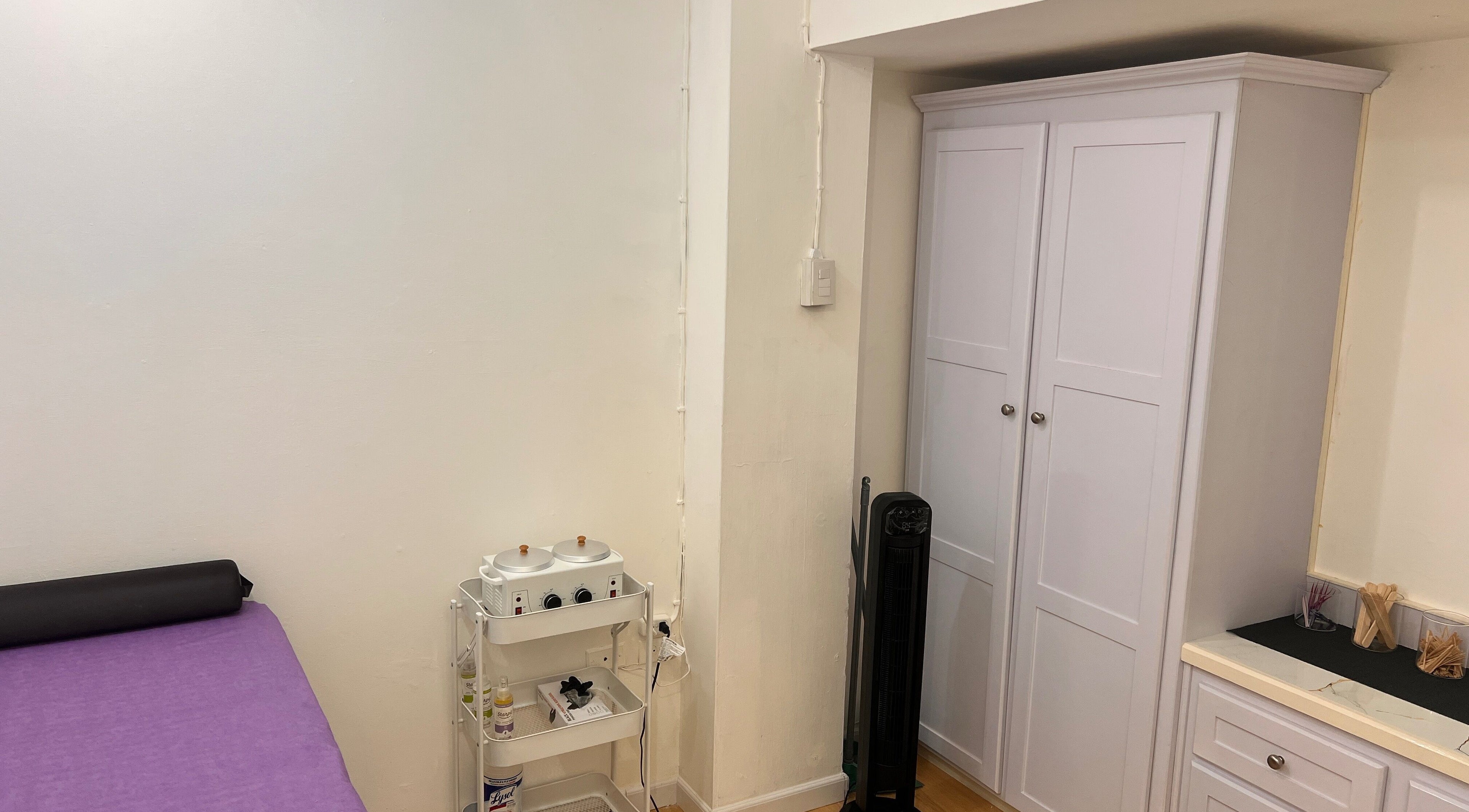 Tranquil treatment room at ACEluxeluminance in Port Of Spain, featuring a massage table and white cabinets.