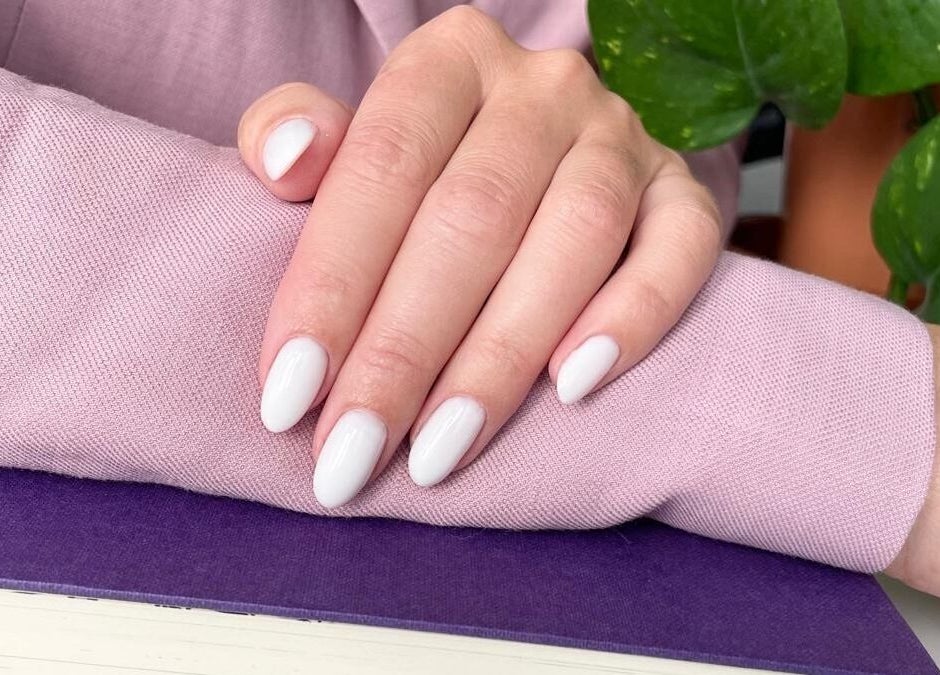 Elegant white manicure at Nail Room in Bromley, England, GB, showcasing polished nails with plant decor.