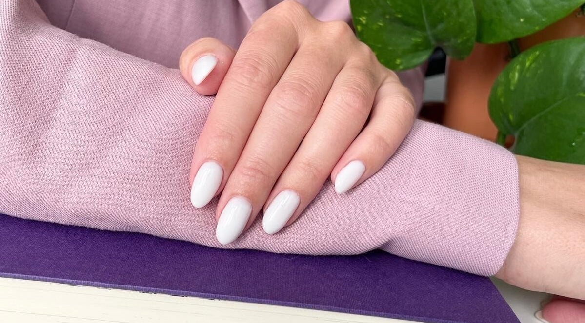 Elegant white manicure at Nail Room in Bromley, England, GB, showcasing polished nails with plant decor.