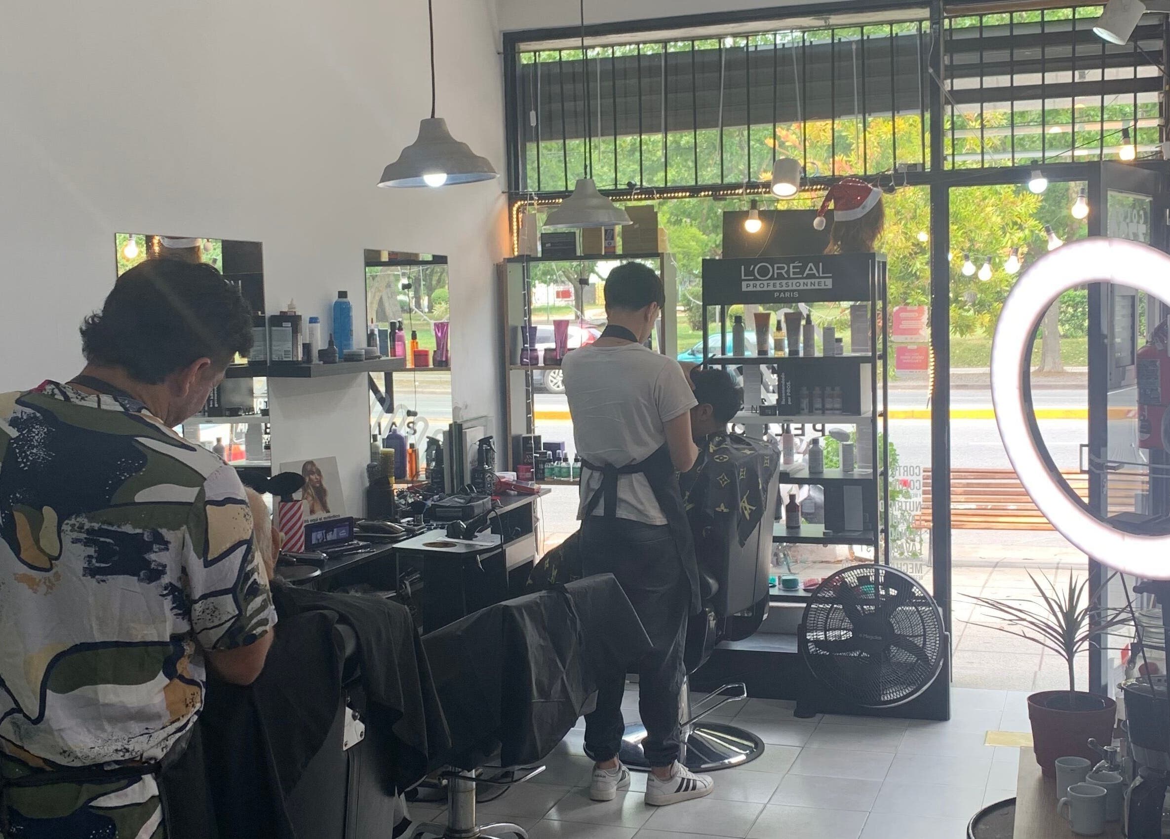 Interior moderno de ESAN Peluquerias, Mar del Plata, con estilistas trabajando junto a un ventanal iluminado.