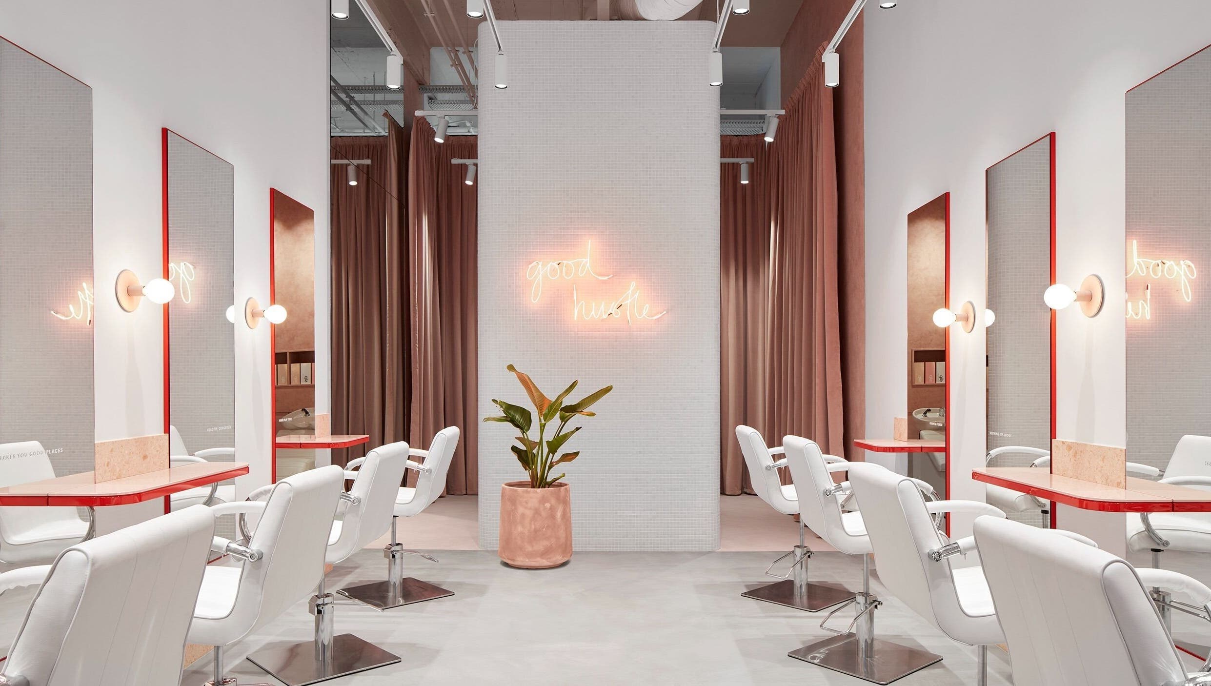 Stylish salon interior at The Blow Australia, Melbourne, Victoria, AU with white chairs and neon sign.