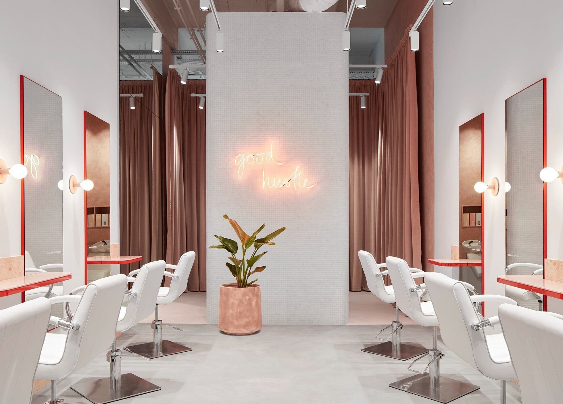 Stylish salon interior at The Blow Australia, Melbourne, Victoria, AU with white chairs and neon sign.