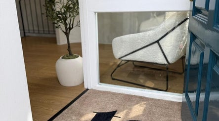 Welcoming entrance to Missclinicaesthetics in Bath, England, GB with a cozy chair and plant inside.