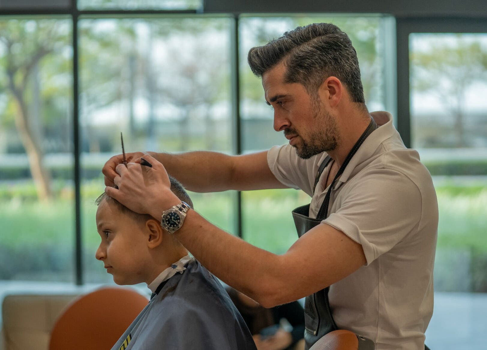 Barber styling a young boy's hair at Bebek Gents Salon L.L.C, Dubai, AE, showcasing expert grooming services.