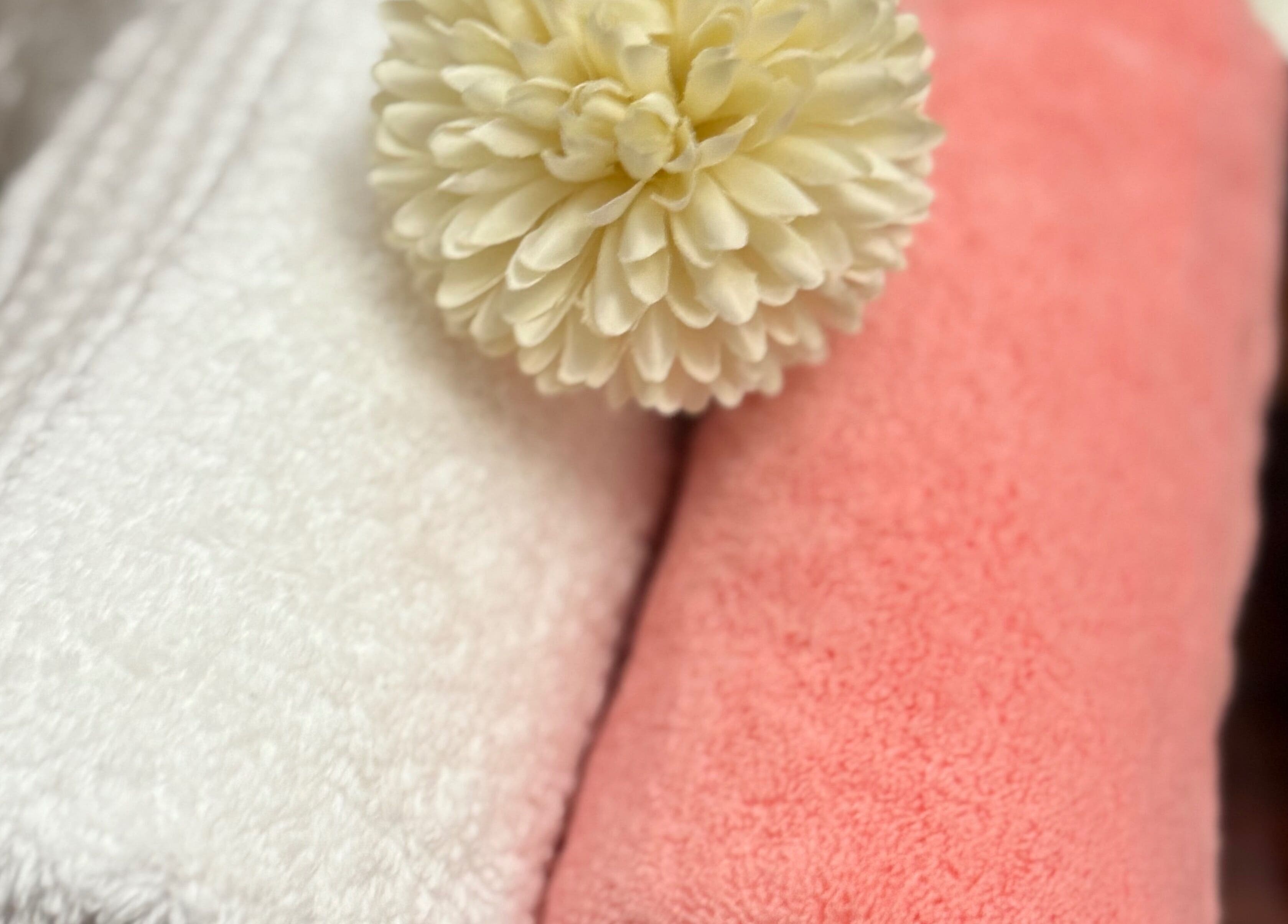 Toallas blancas y rosas con flor en Adri Oliver Masajes Bienestar, Donostia / San Sebastián, Euskadi, ES.