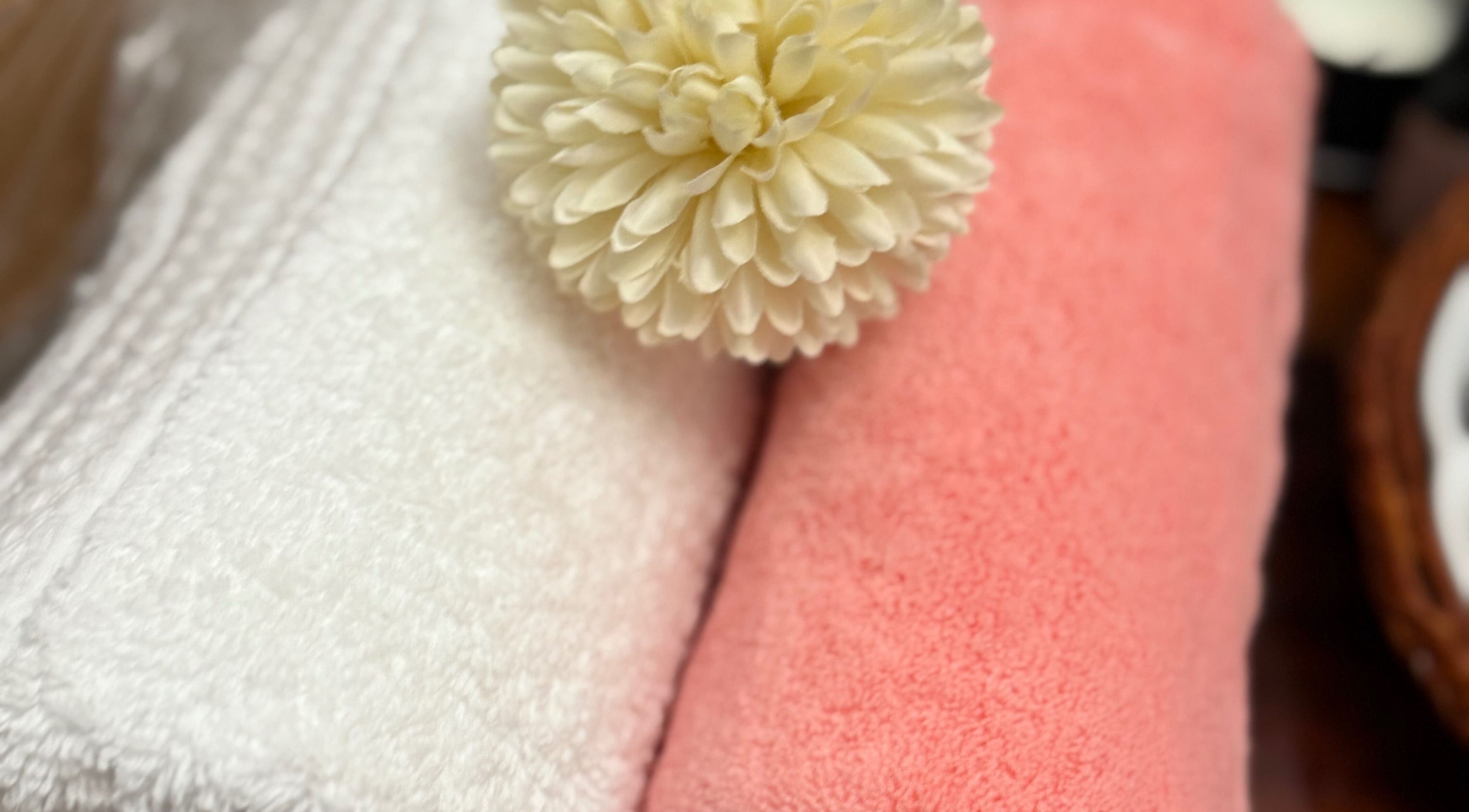 Toallas blancas y rosas con flor en Adri Oliver Masajes Bienestar, Donostia / San Sebastián, Euskadi, ES.