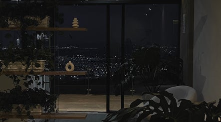 Vista nocturna desde Cavilé en Zibatá, Querétaro, MX, con plantas decorativas y una silla minimalista.