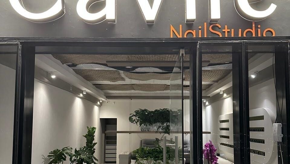 Entrada moderna de Cavilé Nail Studio en Zibatá, Querétaro, MX con iluminación cálida y vegetación decorativa.