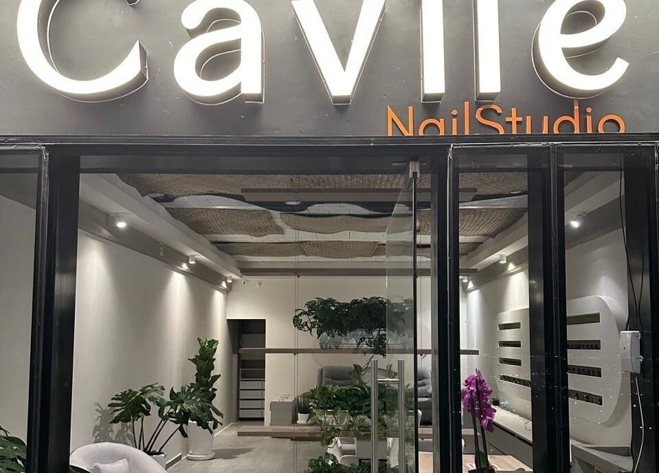 Entrada moderna de Cavilé Nail Studio en Zibatá, Querétaro, MX con iluminación cálida y vegetación decorativa.