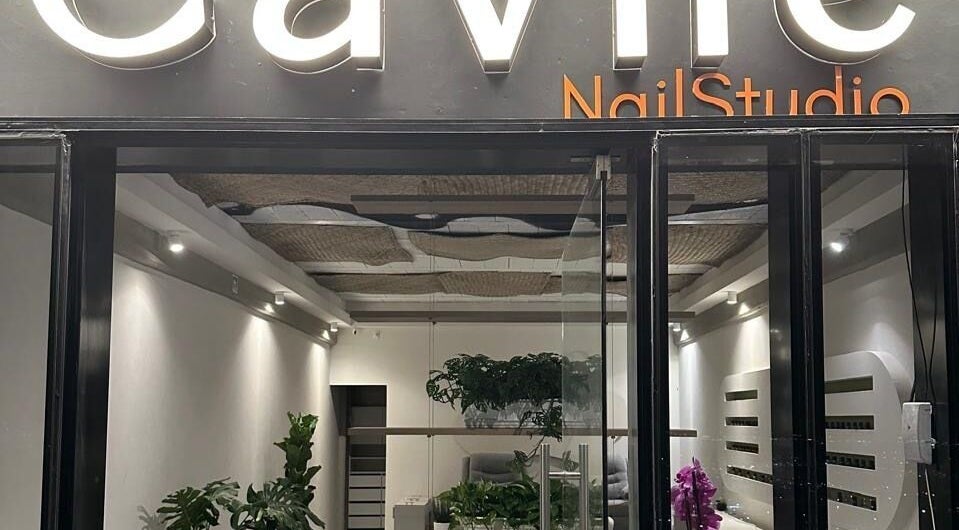 Entrada moderna de Cavilé Nail Studio en Zibatá, Querétaro, MX con iluminación cálida y vegetación decorativa.