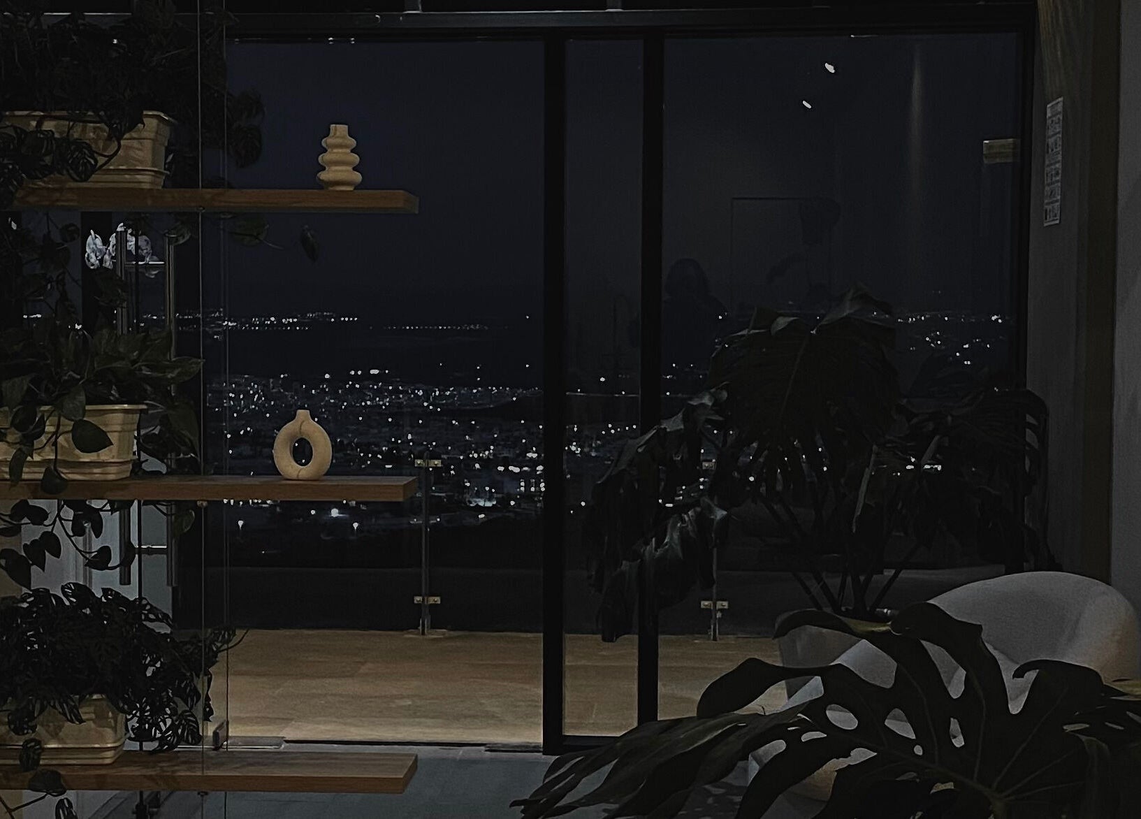 Sala elegante de Cavilé con vista nocturna de Zibatá, Querétaro, MX, iluminada por la ciudad.