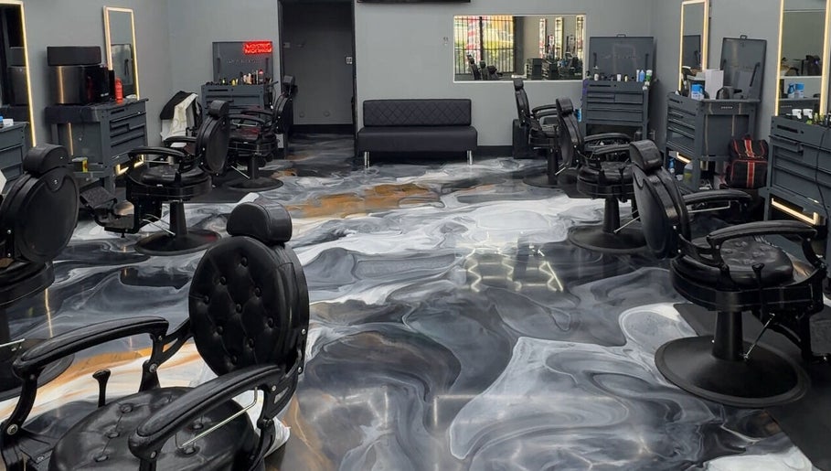 Sleek interior of The Spot barbershop in Los Angeles, California, US with modern black chairs and swirling floor design.