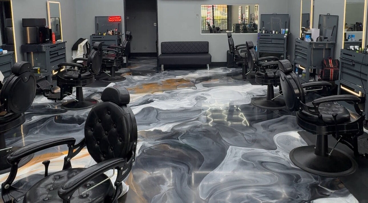 Sleek interior of The Spot barbershop in Los Angeles, California, US with modern black chairs and swirling floor design.