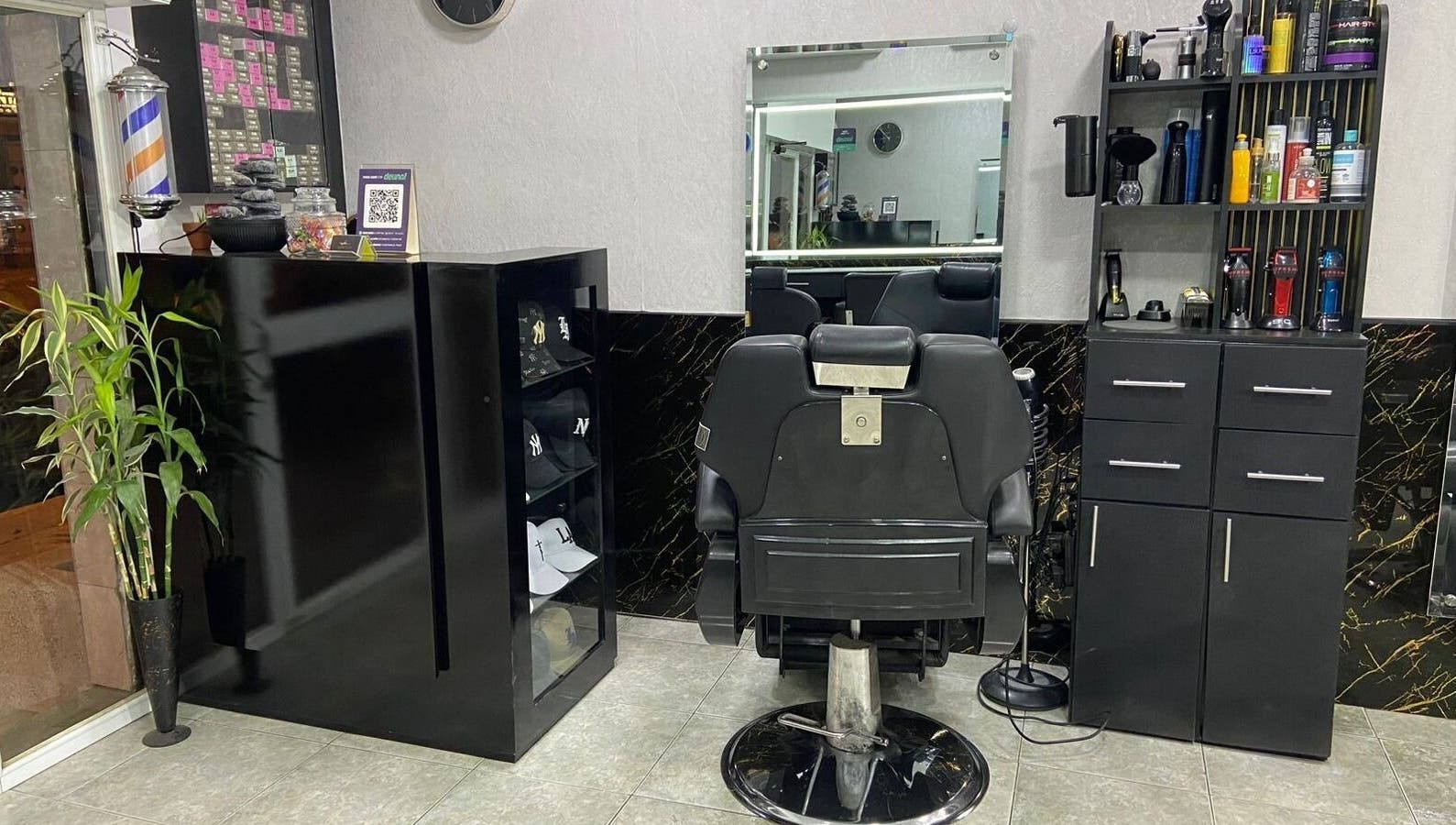 Interior sofisticado de Elegante en Manta, Manabí, EC con silla de barbero y estantes organizados.