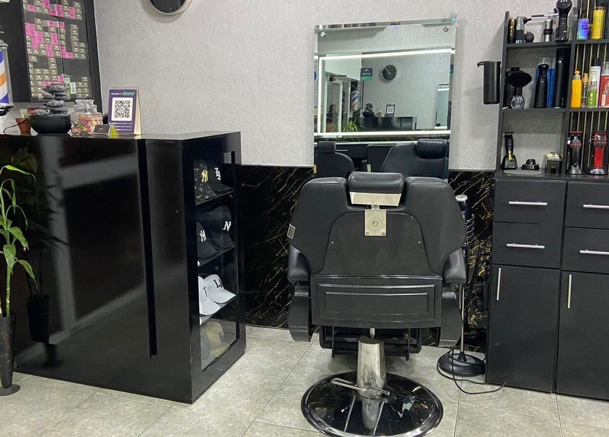 Interior sofisticado de Elegante en Manta, Manabí, EC con silla de barbero y estantes organizados.