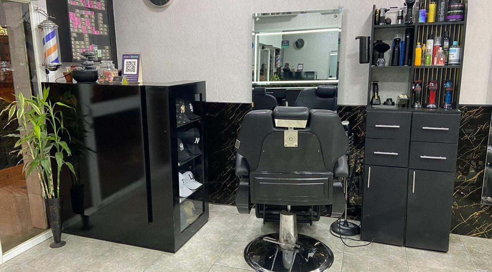 Interior sofisticado de Elegante en Manta, Manabí, EC con silla de barbero y estantes organizados.