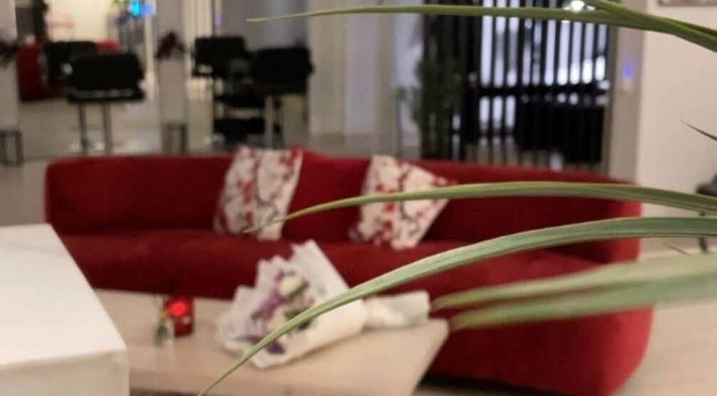 زاوية استرخاء بصالون فوز للتزين النسائي في الطائف، منطقة مكة، تضم أريكة حمراء مريحة.