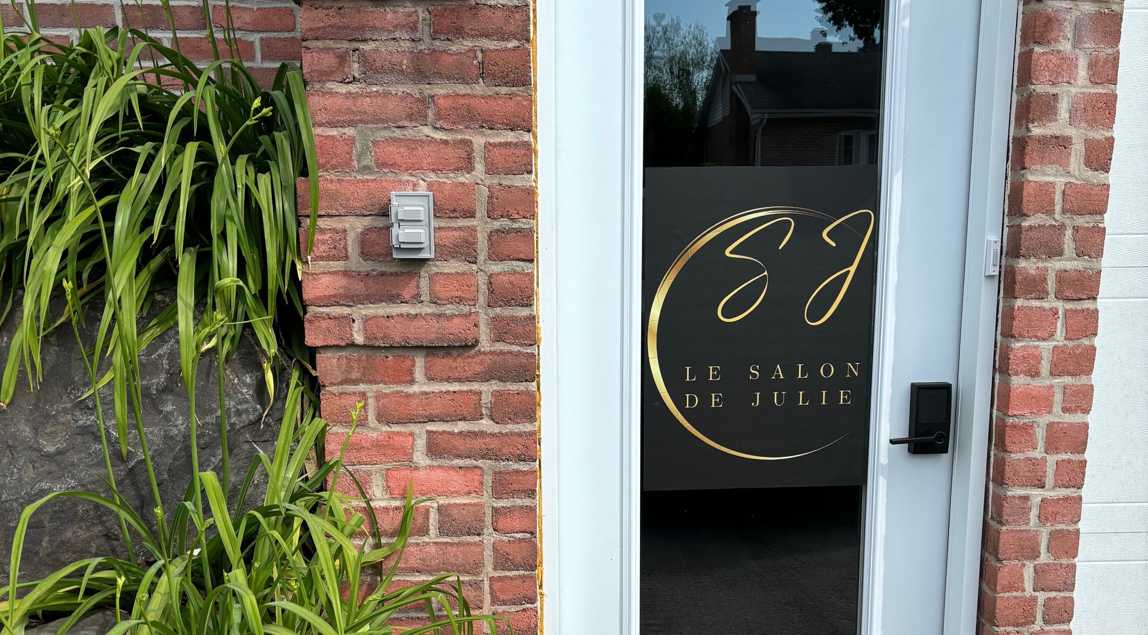 Entrée moderne de Le Salon de Julie à Granby, Québec, CA, avec une porte vitrée et un mur en briques.