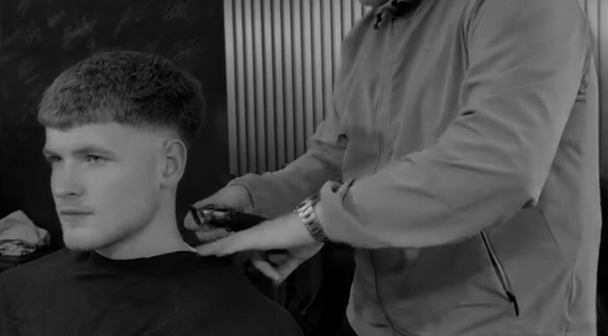 Barber styling a man's hair with clippers at Twinz Trimz, Kilmarnock, Scotland, GB.