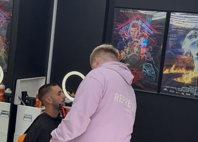 Stylist giving a modern haircut at Twinz Trimz, Kilmarnock, Scotland, GB. Posters adorn the salon's stylish interior.
