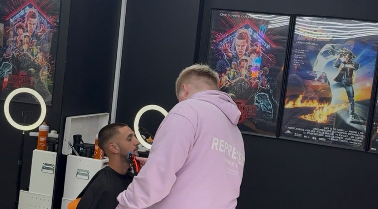 Stylist giving a modern haircut at Twinz Trimz, Kilmarnock, Scotland, GB. Posters adorn the salon's stylish interior.