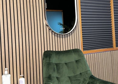 Chic lounge area at Studio Carine | Laser & Peau, Longueuil, Québec, CA with green chair and modern decor.