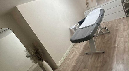 A tranquil treatment room at Bychloeleigh in Wales, GB, featuring a massage table and minimalist decor.