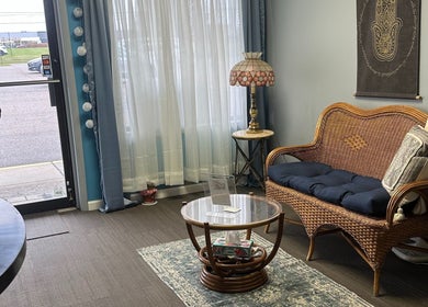 Inviting seating area at Sleepy Koi Bodyworks, Swartz Creek, Michigan, US with wicker chair and elegant decor.
