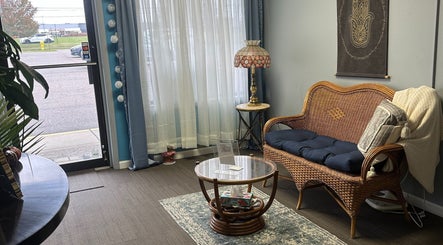 Inviting seating area at Sleepy Koi Bodyworks, Swartz Creek, Michigan, US with wicker chair and elegant decor.