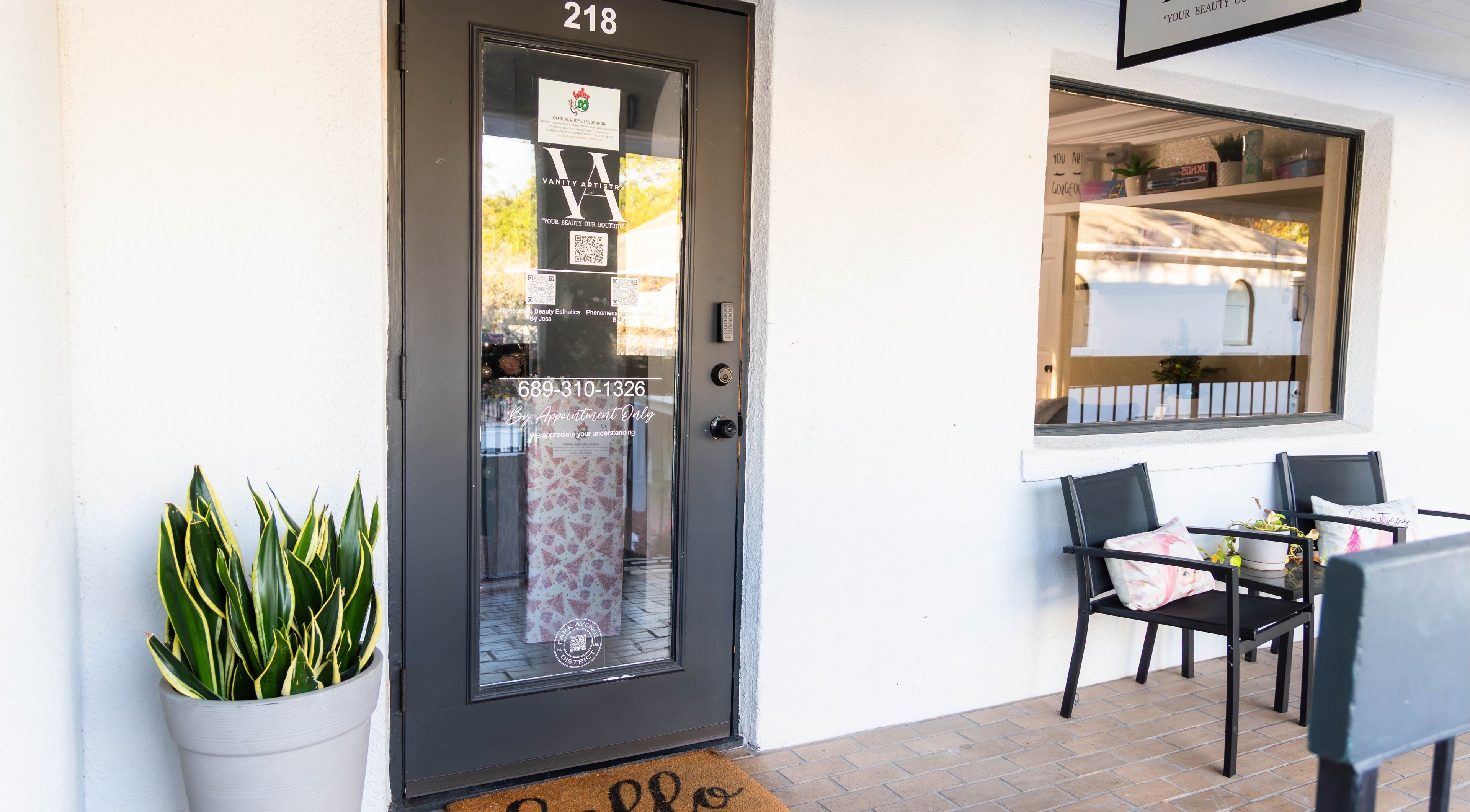 The entrance to Vanity Artistry in Winter Park, Florida, US, featuring a glass door and cozy outdoor seating.