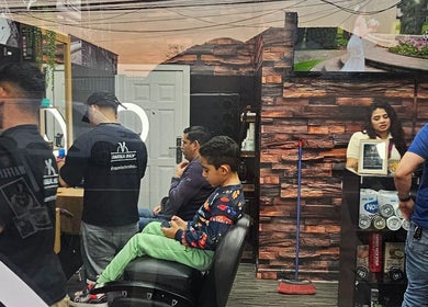 Inside VEGASBARBERSHOP in San Miguel, Región Metropolitana, CL - barber with clients and reception area.