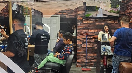 Inside VEGASBARBERSHOP in San Miguel, Región Metropolitana, CL - barber with clients and reception area.