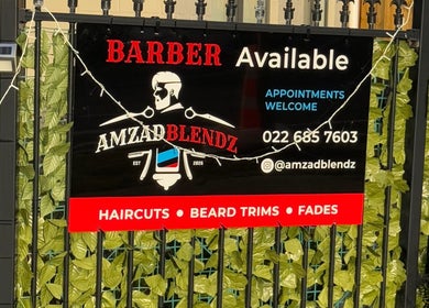 Amzadblendz barber sign in Auckland, Auckland, NZ displaying services and contact info amidst green leaves.