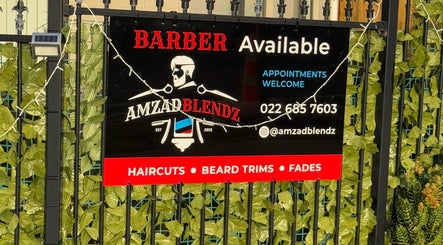 Amzadblendz barber sign in Auckland, Auckland, NZ displaying services and contact info amidst green leaves.