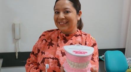 Dentista en Smileclinic Buenos Aires enseñando higiene oral con modelo dental.