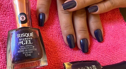 Mãos com esmalte escuro na Toque de Mestra, Minas Gerais, BR, sobre toalha rosa.