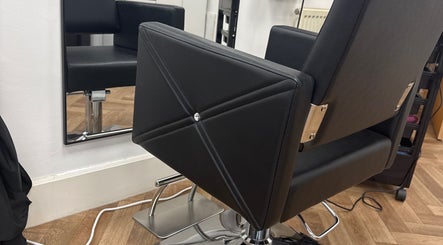 Sleek black salon chair at Maria Salon in London, England, GB, showcasing modern elegance and comfort.