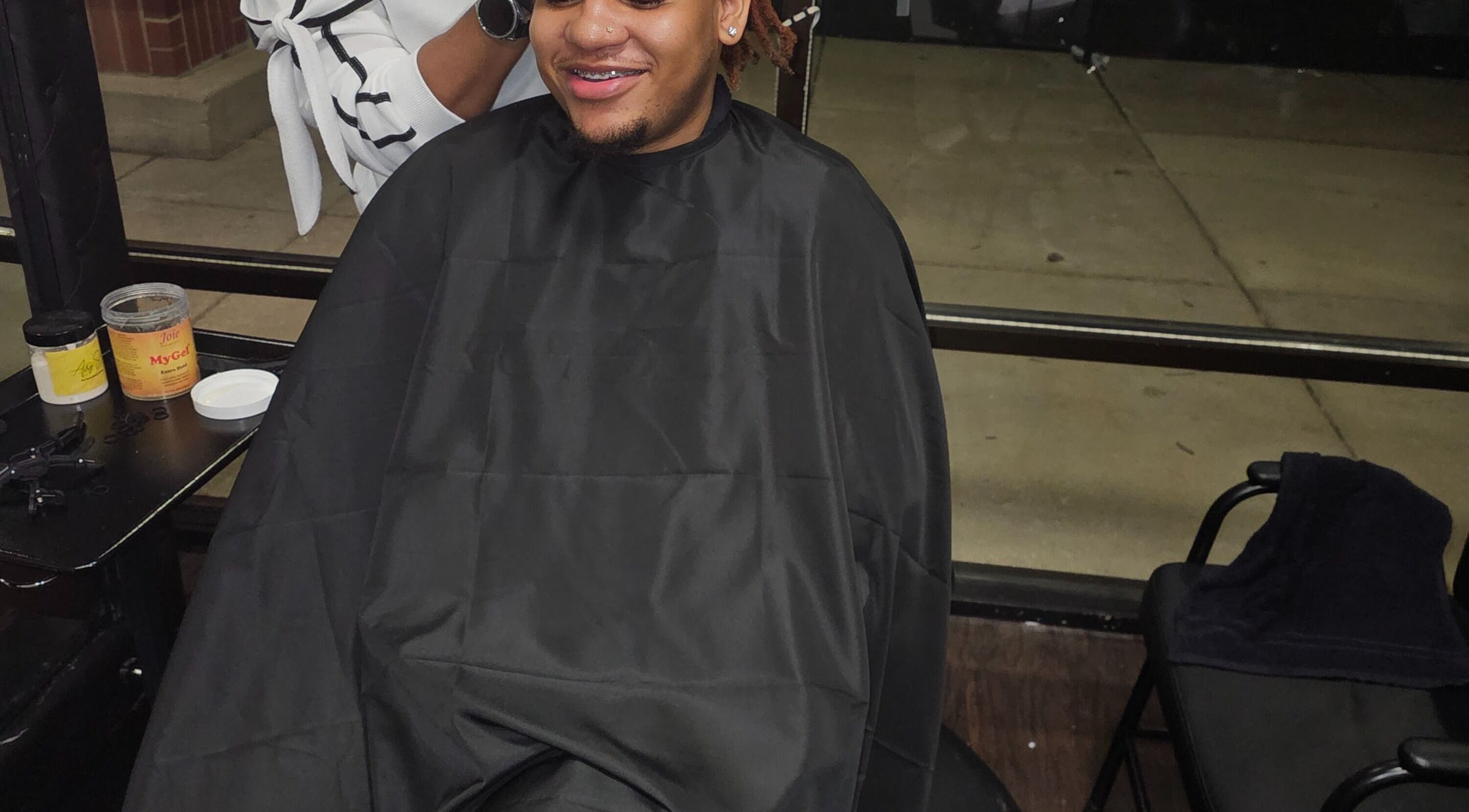 Smiling client in a salon cape at MICKnifEcYnt Artistry, Oswego, Illinois, US.