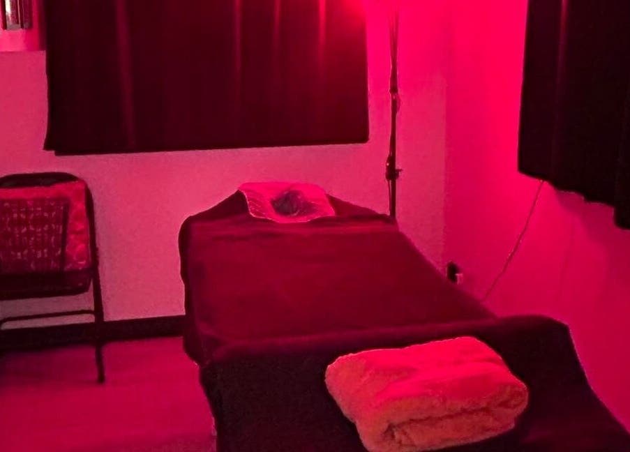 Cozy massage room at Revive Massage Therapy, Guernsey, Vale, GG, illuminated by calming red light.