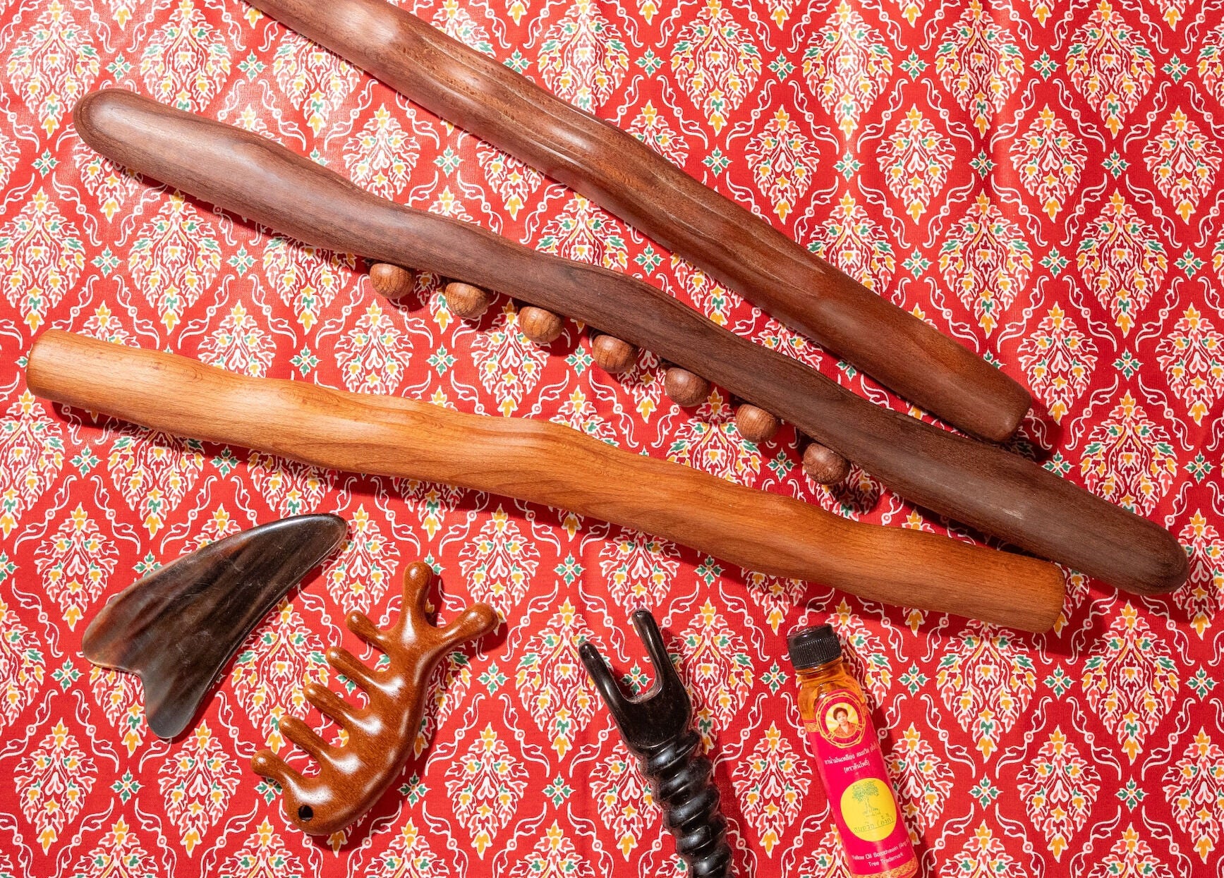 Traditional Thai massage tools at Thai Time Wellness Spa, Singapore, SG, on a vibrant red patterned fabric.