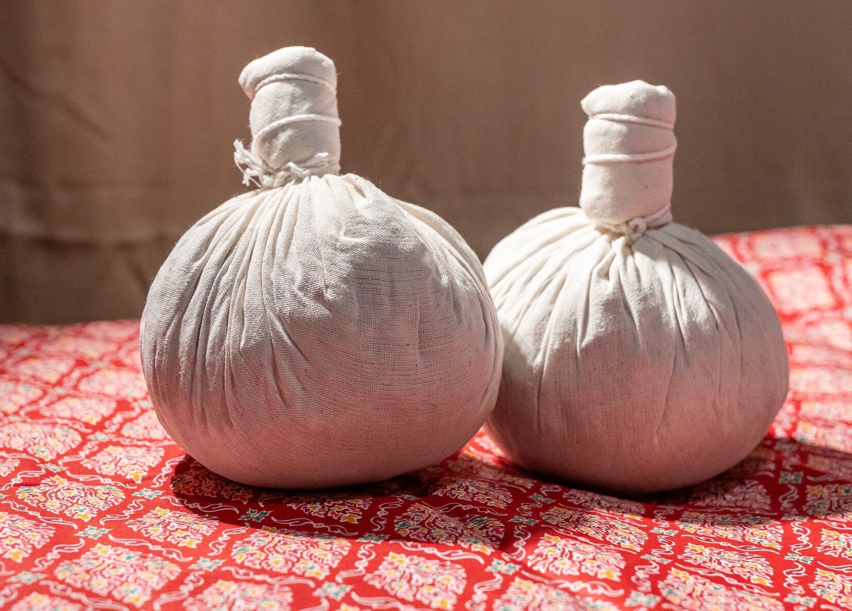 Herbal pouches at Thai Time Wellness Spa, Singapore, SG on a vibrant red patterned cloth.