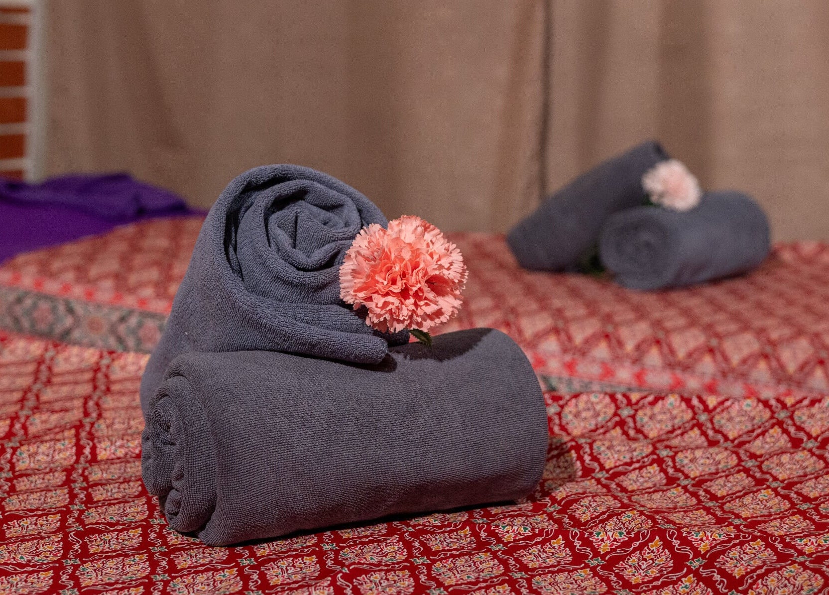 Rolled towels with pink flowers at Thai Time Wellness Spa, Singapore, SG, enhancing a serene ambiance.