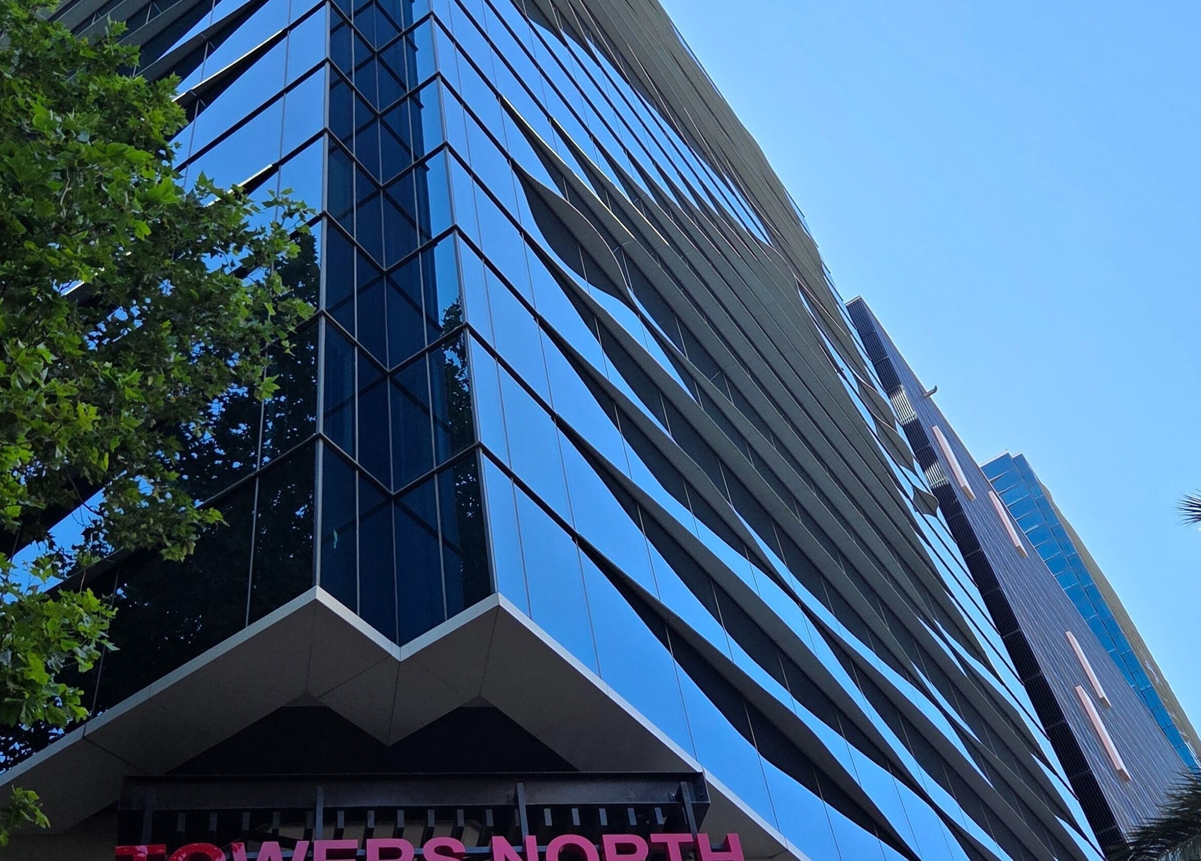 Modern glass building housing White Sage (Pty) Ltd at Cape Town, Western Cape, ZA with tree reflections.