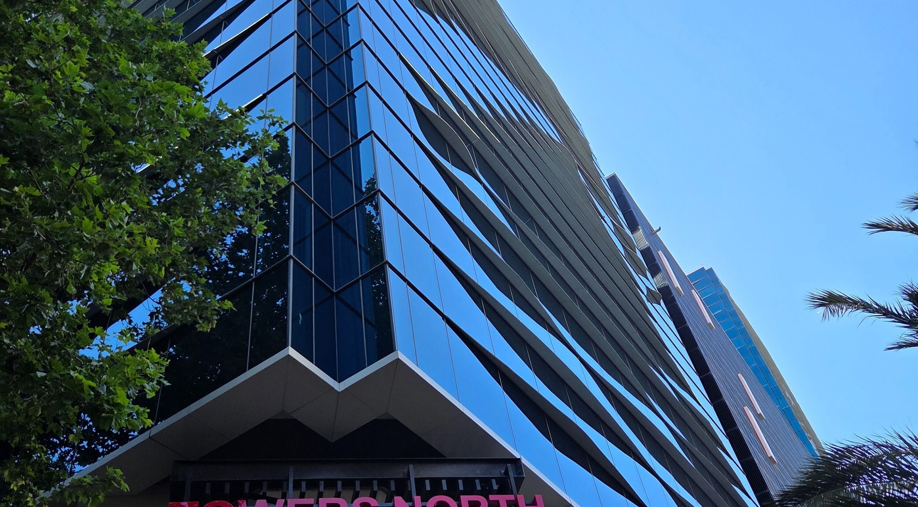 Modern glass building housing White Sage (Pty) Ltd at Cape Town, Western Cape, ZA with tree reflections.