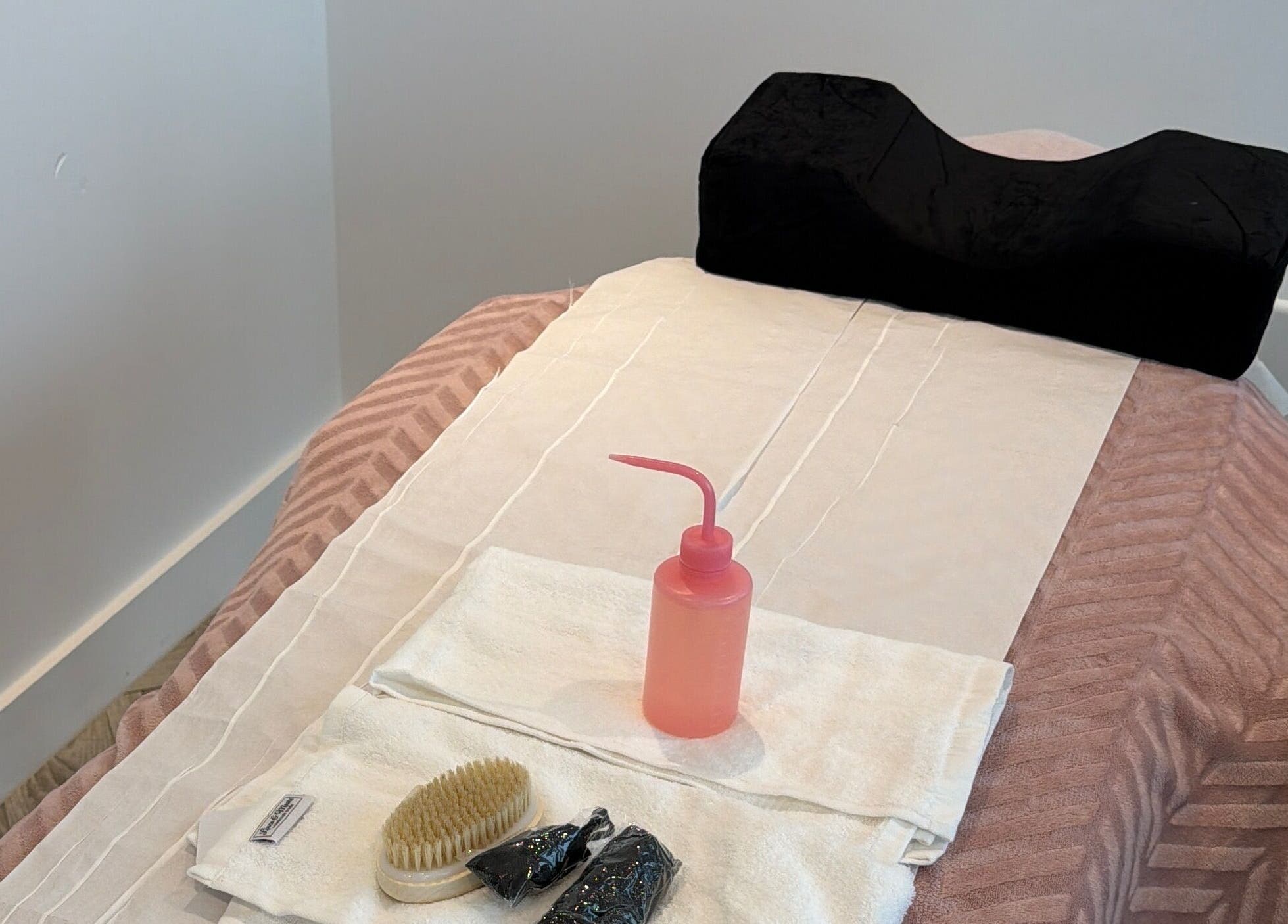 Massage table set up at sol.lymphatic in Salford, England, GB with towels, brush, and lotion bottle.