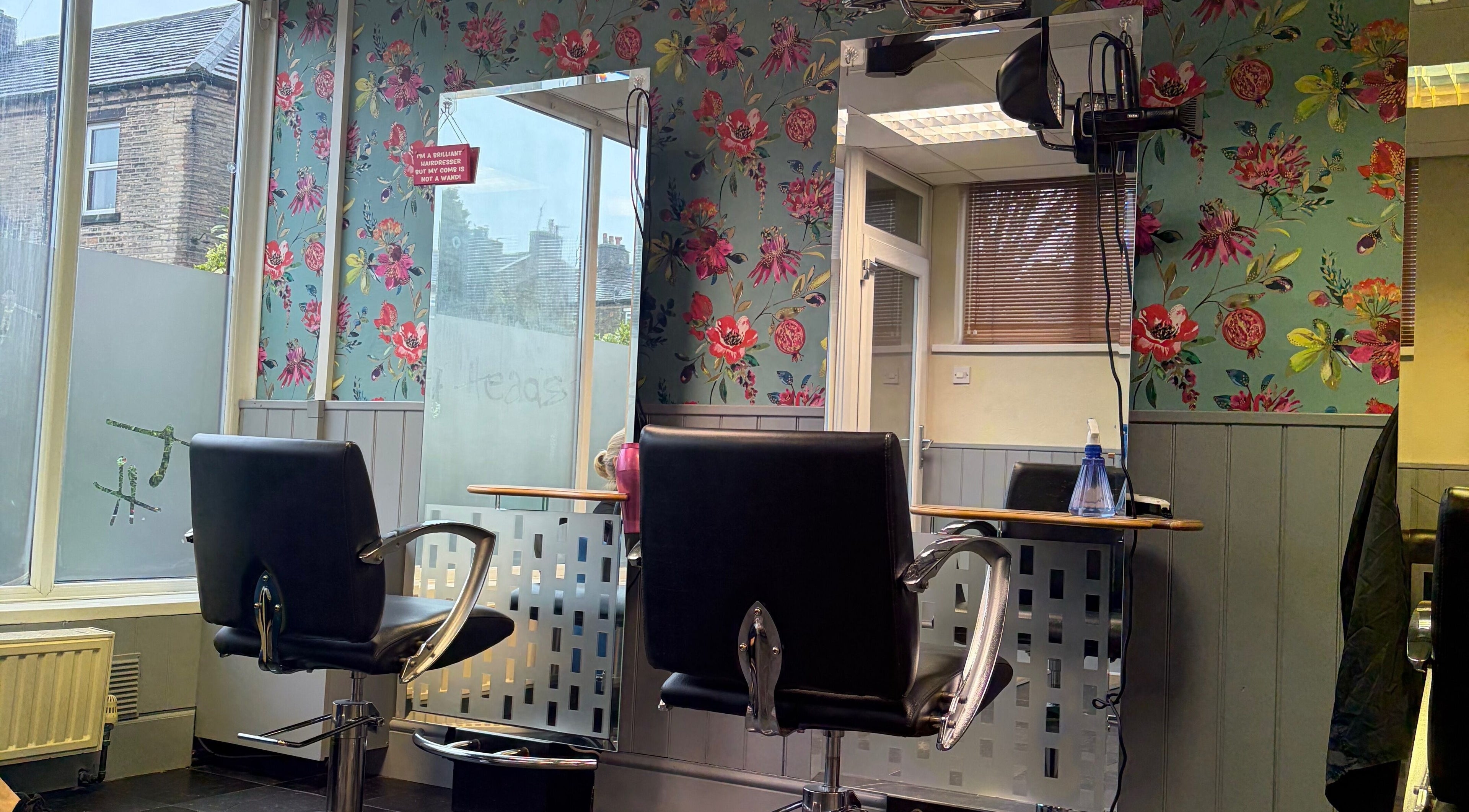 Stylish salon interior at Hair by Sienna, Northowram, England, GB, featuring floral wallpaper and modern styling chairs.