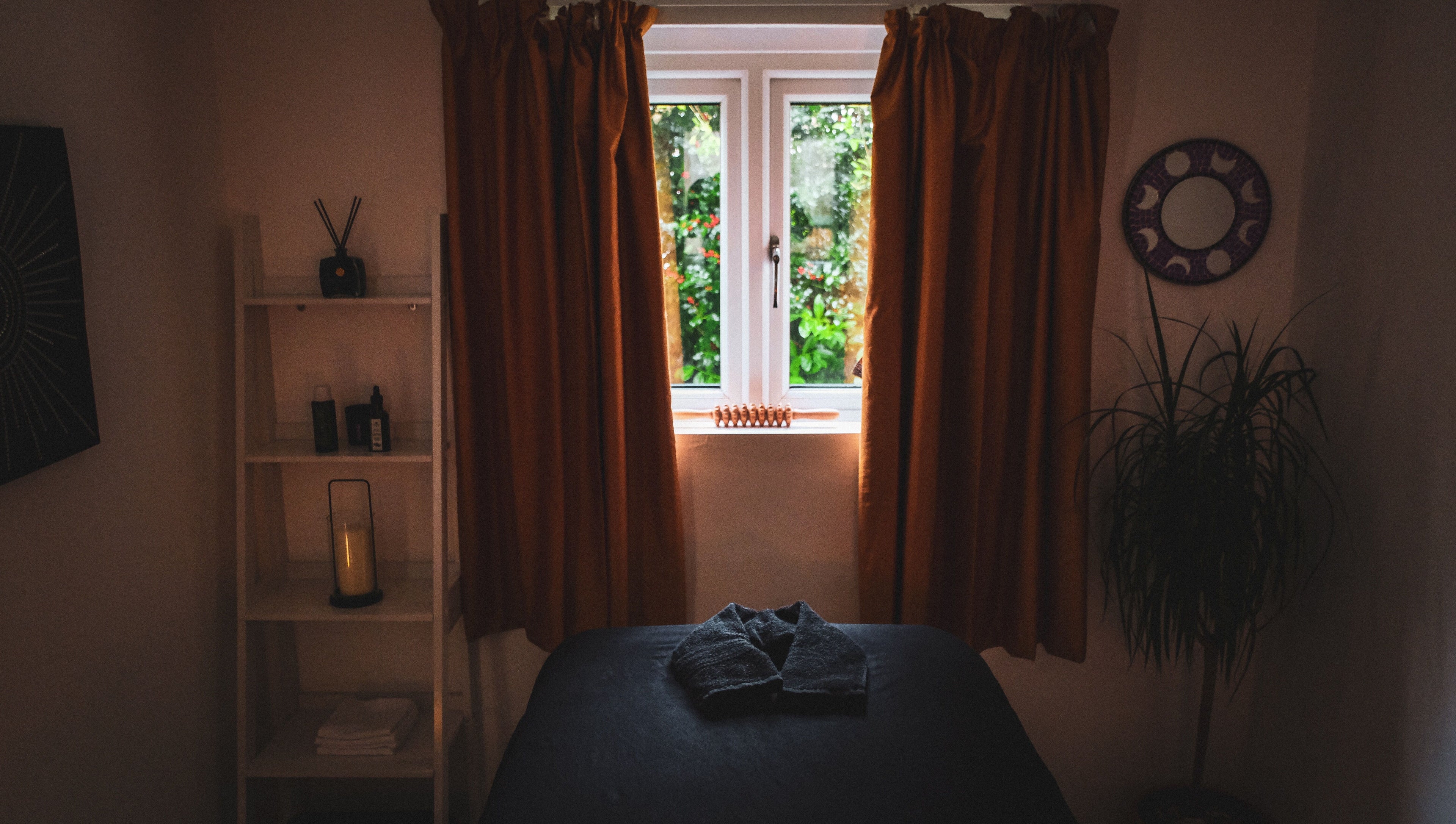 Serene massage room at Kaph Massage Therapies in Selling, England, GB with warm lighting and a window view.